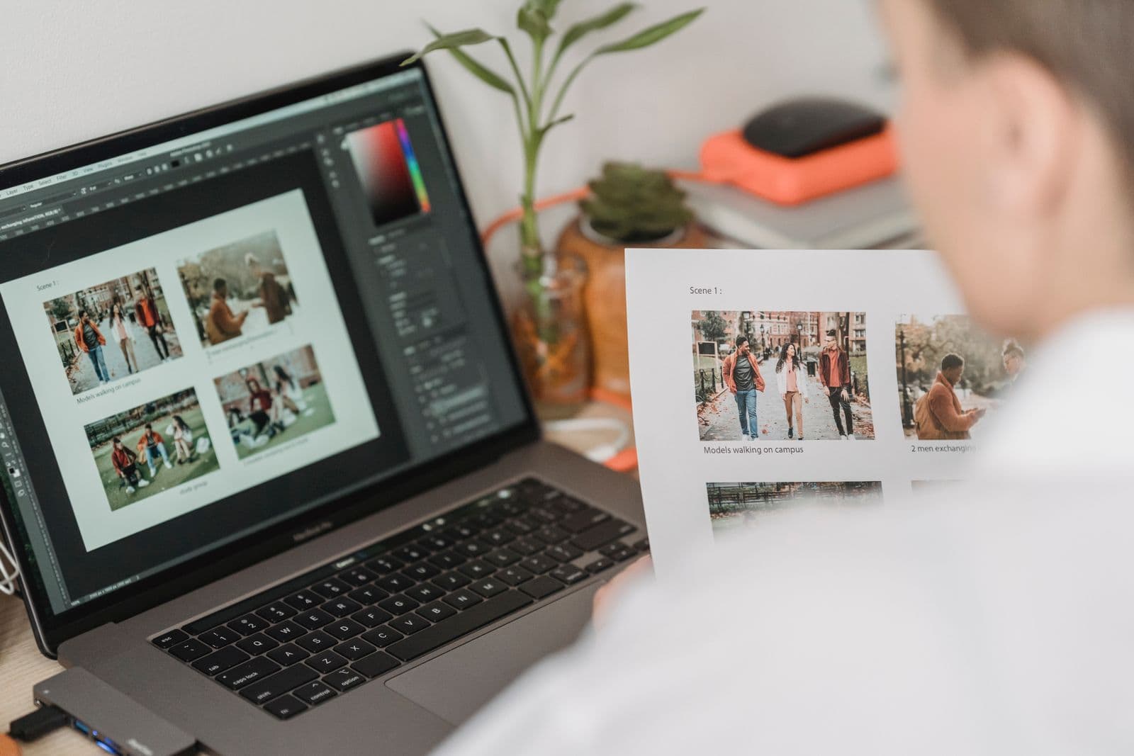 A person reviewing a grid of photo thumbnails on a laptop screen, with a printed contact sheet in hand